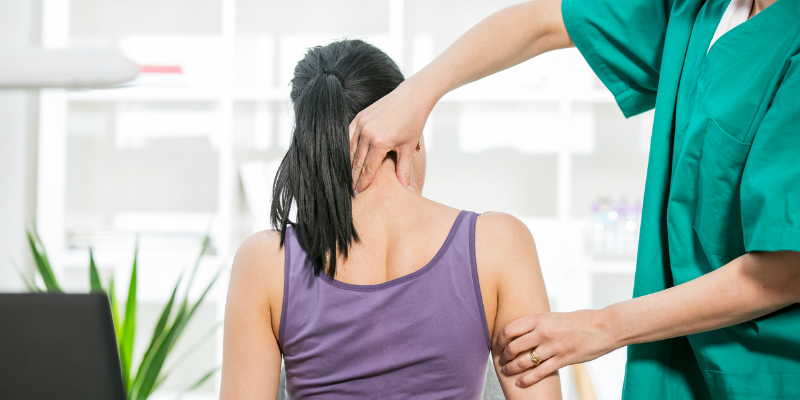 Chiropractor stretches female patient neck muscles